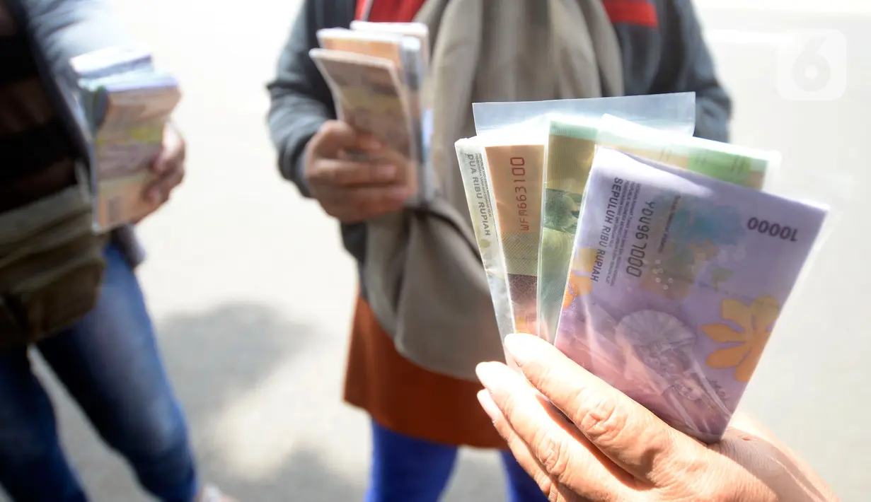 Penjual jasa penukaran uang menawarkan uang baru berbagai pecahan kepada pengguna jalan di kawasan Bintaro Sektor 2, Jakarta Selatan, Selasa (12/05/2020). Pembeli uang kertas baru yang biasanya ramai menjelang Lebaran, kini sepi di tengah pandemi virus corona Covid-19. (merdeka.com/Dwi Narwoko)