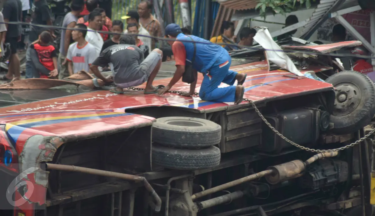 Petugas berusaha mengevakuasi bangkai bus Trans Semarang yang menabrak pangkalan ojek di Jalan Sultan Agung, Semarang, Minggu (17/7). Akibat kejadian tersebut, sedikitnya 23 orang mengalami luka-luka. (Liputan6.com/Gholib)