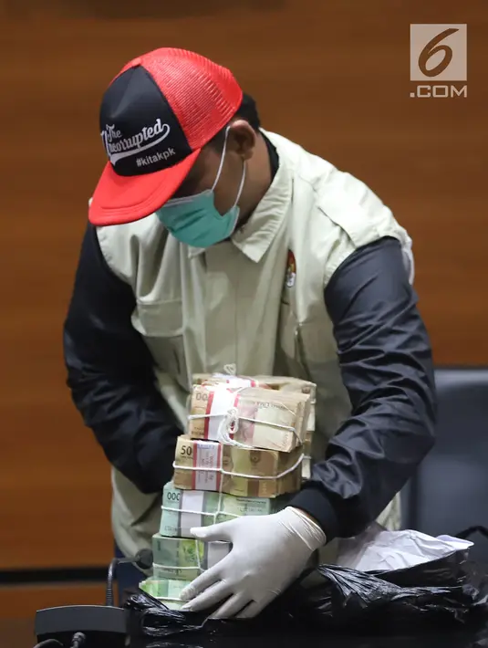 Petugas KPK menunjukkan barang bukti uang saat jumpa pers terkait OTT Bupati Cirebon Sunjaya Purwadi Sastra di Gedung KPK, Jakarta, Kamis (25/10). Sunjaya diduga menerima uang Rp 6,65 miliar terkait jual beli jabatan. (Liputan6.com/Herman Zakharia)