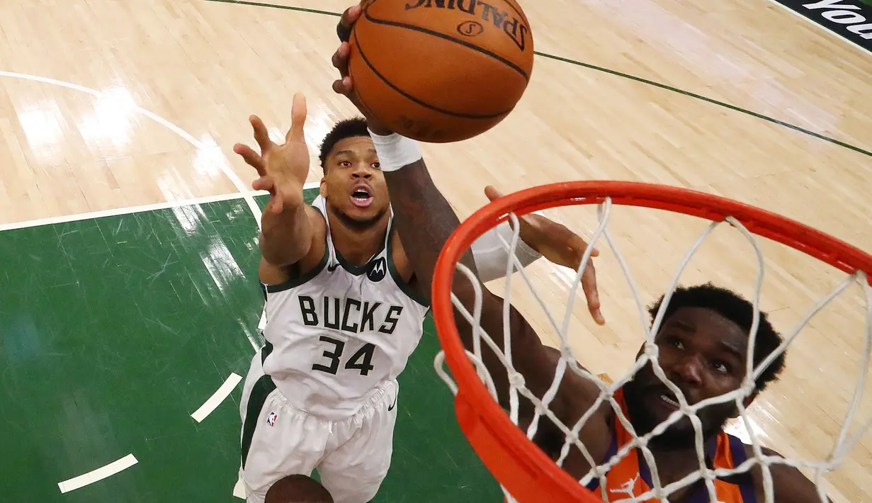 Giannis Antetokounmpo (kiri) memainkan peran vital pada kuarter terakhir ini. Dirinya berhasil memblok usaha Deandre Ayton (kanan) memasukkan bola, sehingga Suns gagal menyamakan kedudukan. Bucks akhirnya mengunci kuarter keempat dengan skor 33-21. (Foto: Getty Images via AFP/Pool/Mark J. Rebilas)