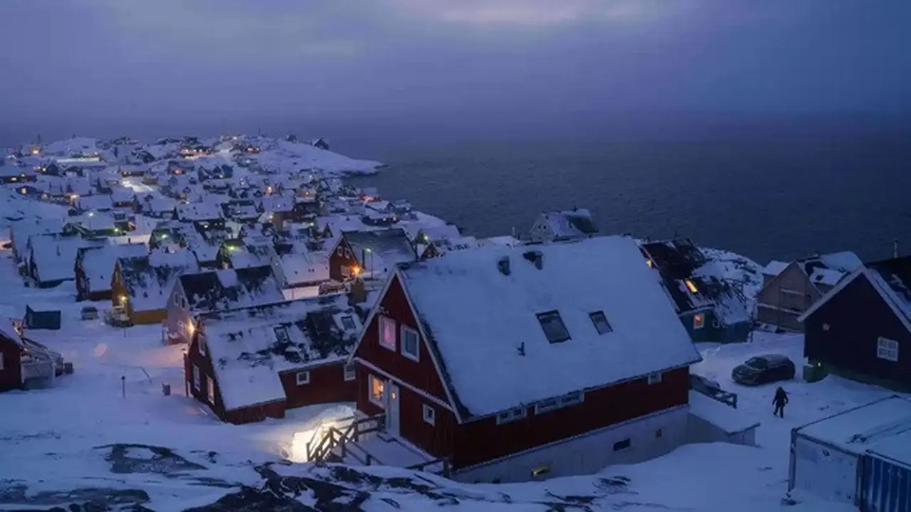 Rumah-rumah yang tertutup salju terlihat di pesisir sebuah teluk laut di Nuuk, Greenland, pada Senin (12/1/2026).