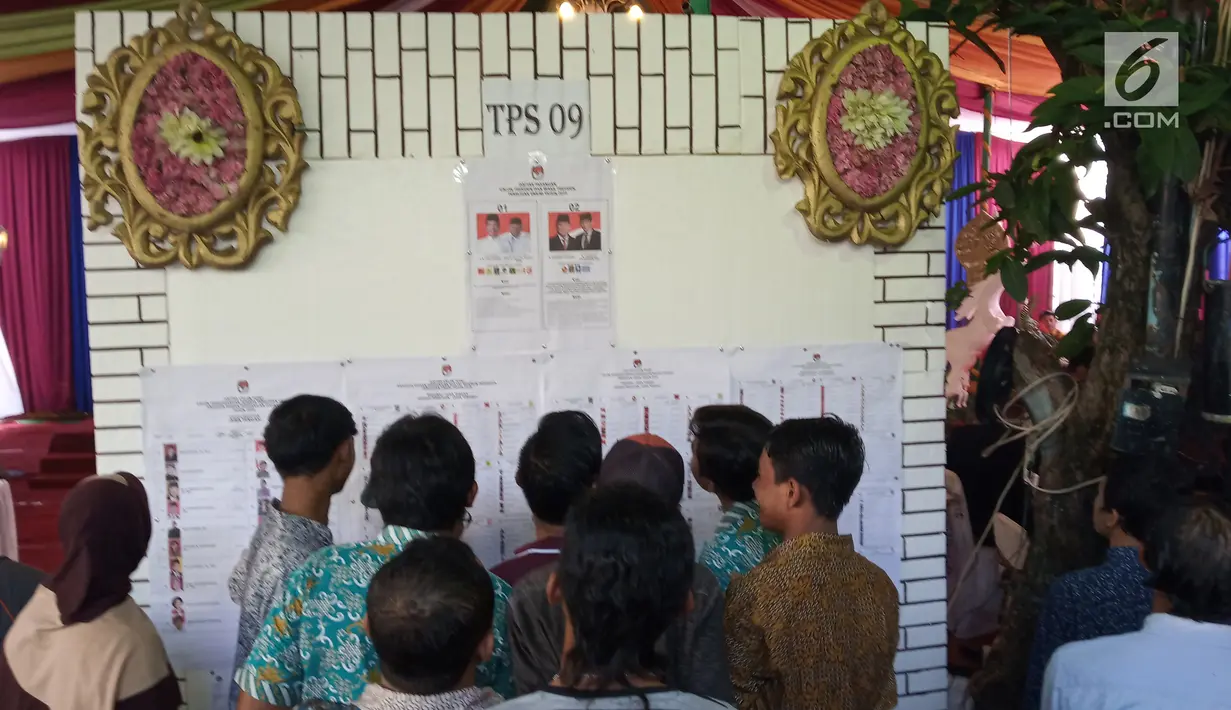 Warga melihat daftar nama caleg pada Pemilu 2019 di TPS 09 Kelurahan Sambirejo yang berkonsep pesta pernikahan di Semarang, Rabu (17/4). TPS itu dihiasi dengan dekorasi mewah dan menarik layaknya tempat pesta pernikahan agar semua warga senang ketika datang untuk mencoblos. (Liputan6.com/Gholib)