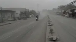 Pengendara sepeda motor melintasi jalan yang tertutup abu vulkanik dari gunung berapi Taal di Lemery, provinsi Batangas, Filipina, Senin (13/11/2020). Erupsi gunung Taal memaksa puluhan ribu orang mengungsi serta membuat sekolah-sekolah dan toko di Manila tutup. (AP/Aaron Favila)