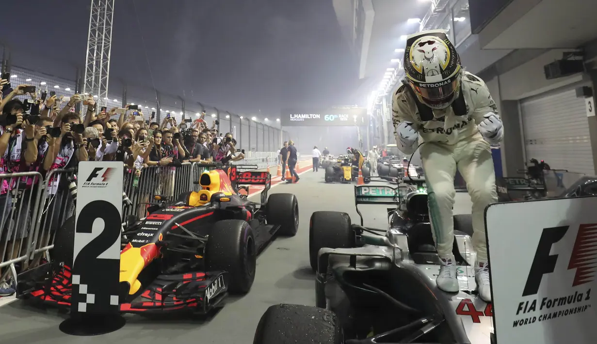 Ekspresi Lewis Hamilton saat berdiri di atas mobilnya usai menjuarai balapan F1 Singapura di Marina Bay City Circuit Singapore, (17/9/2017). (AP/Yong Teck Lim)