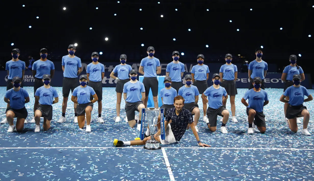 Petenis Rusia Daniil Medvedev berpose dengan trofi juara ATP World Finals serta ball boys dan ball girls di O2 Arena, London, Inggris, Minggu (22/11/2020). Daniil Medvedev menjuarai ATP World Finals usai mengalahkan petenis Austria Dominic Thiem pada babak final. (AP Photo/Frank Augstein)