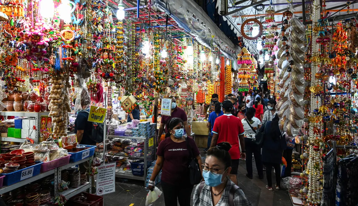 Orang-orang berjalan melintasi sepanjang toko yang menjual ornamen dan dekorasi menjelang Diwali, festival cahaya bagi umat Hindu, di distrik Little India di Singapura pada 23 Oktober 2020. (Photo by Roslan RAHMAN / AFP)