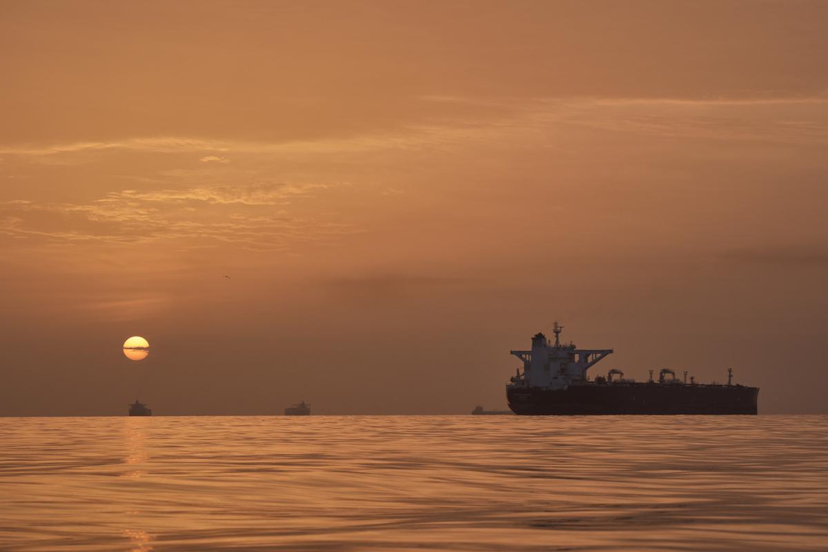 Matahari terbit di balik kapal tanker yang berlabuh di Selat Hormuz di lepas pantai Pulau Qeshm, Iran, Sabtu, 18 April 2026. (AP Photo/Asghar Besharati)
