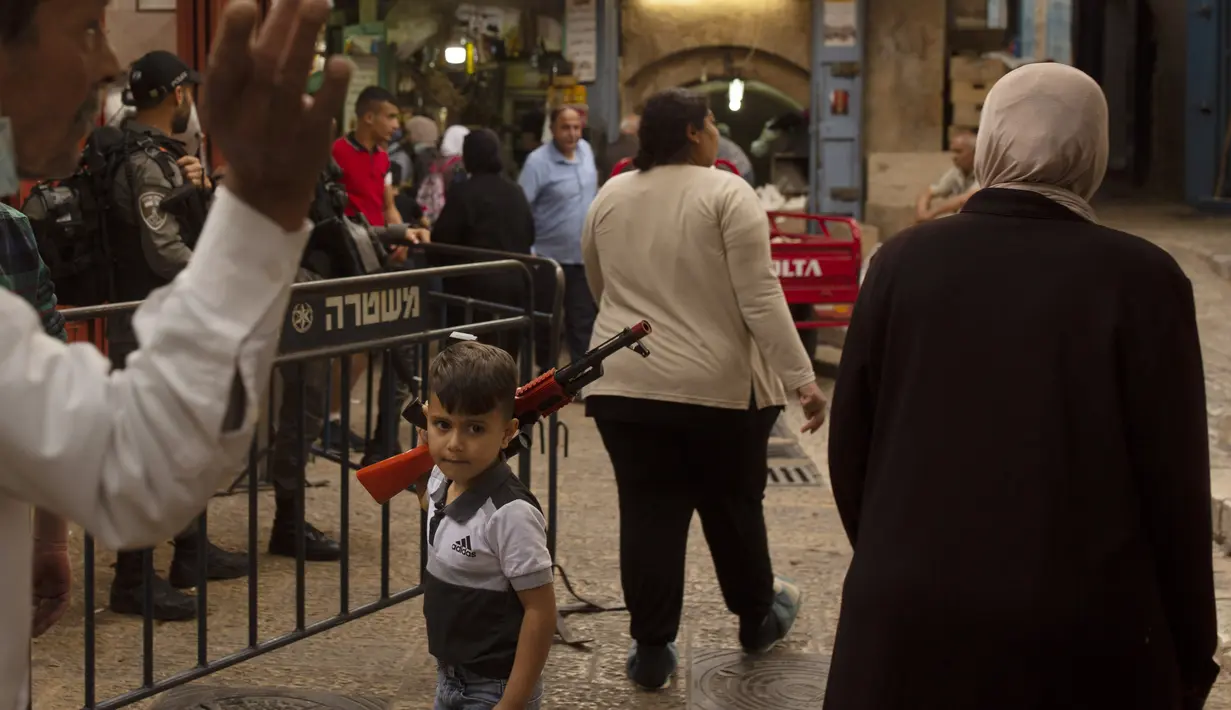 Seorang anak Palestina membawa senjata mainan di Kota Tua Yerusalem, selama bulan suci Ramadhan, Senin  (19/4/2021). Bentrokan serupa terjadi setiap malam sejak Ramadhan dimulai pekan lalu. (AP Photo/Maya Alleruzzo)