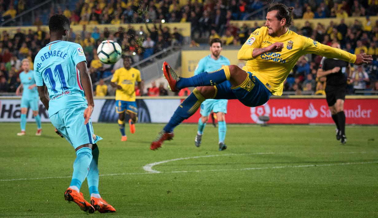 Pemain Las Palmas, Matias Aguirregaray berebut bola dengan  pemain Barcelona, Ousmane Dembele pada jornada ke-26 La Liga 2017-2018 di Estadio Gran Canaria, Kamis (1/3). Barcelona gagal menang karena tuan rumah menahan imbang 1-1. (DESIREE MARTIN/AFP)
