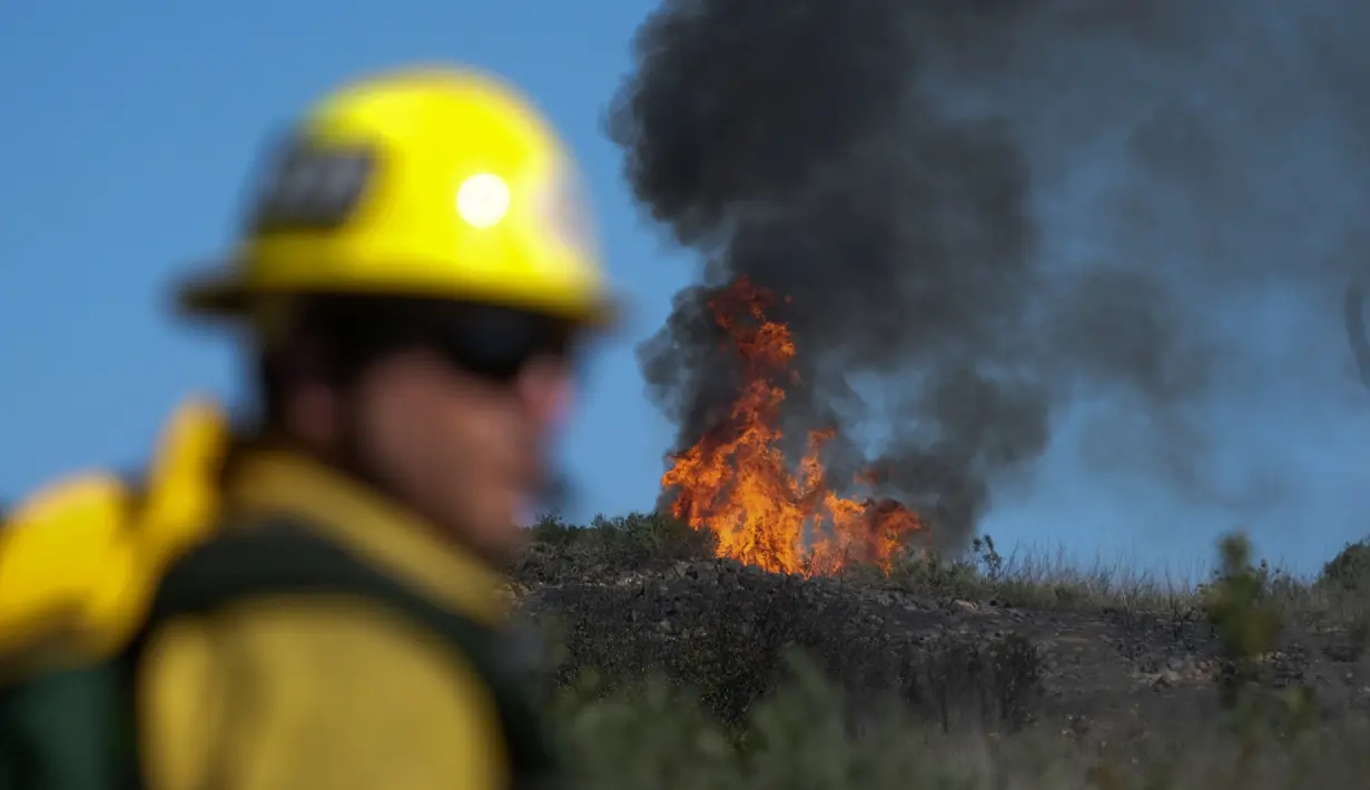 Petugas pemadam kebakaran bekerja pada kebakaran hutan di dekat rumah di Whittier, California, Kamis (10/2/2022). Setidaknya dua rumah hancur dalam kebakaran semak yang menghitamkan sekitar empat hektar di daerah Whittier. (AP Photo/Ringo H.W. Chiu)