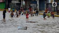 Anak-anak bermain air saat banjir menggenangi Jalan Jatinegara Barat, Jakarta, Kamis (2/1/2020). Hujan yang terjadi kemarin malam membuat Kali Ciliwung meluap ke jalan. (merdeka.com/Imam Buhori)