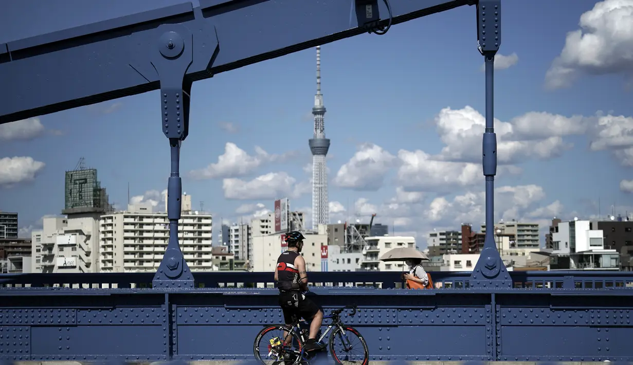 Seorang pria dengan sepeda berhenti di jembatan di Tokyo, Senin (28/9/2020). Ibukota Jepang mengonfirmasi lebih dari 70 kasus virus corona pada hari Senin. (AP Photo / Eugene Hoshiko)