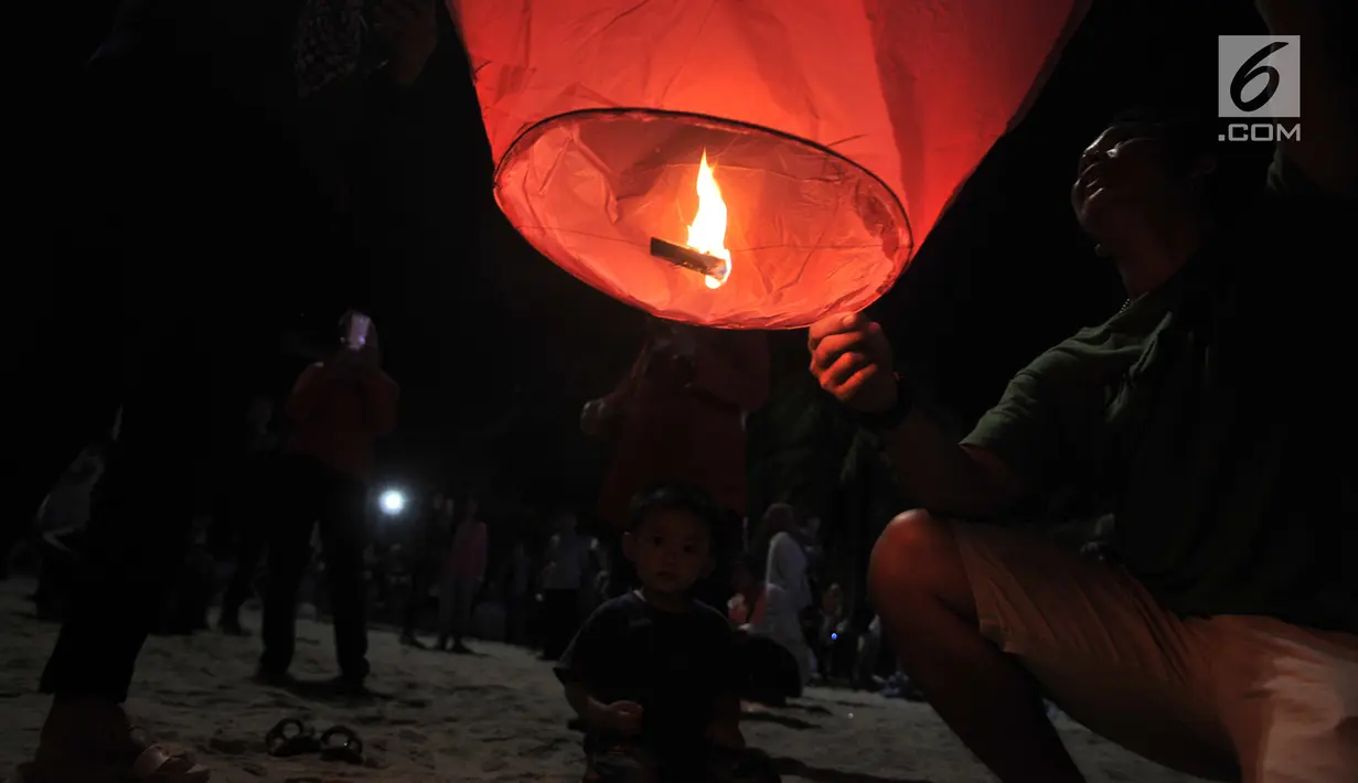 Pengunjung menyalakan api sebelum menerbangkan lampion saat perayaan Tahun Baru Imlek di Pantai Lagoon, Ancol, Jakarta, Selasa (5/2) malam. Sebanyak 500 lampion dilepas dalam  rangka menutup Festival Imlek di Ancol. (Merdeka.com/Iqbal S Nugroho)