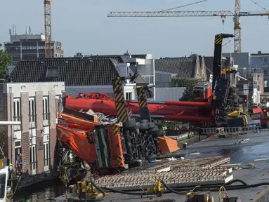 Dua mesin derek jatuh ke rumah warga di Alphen aan den Rijn, Belanda, Senin (3/8/2015) waktu setempat. Dua mesin derek yang sedang memperbaiki jembatan ambruk ke rumah yang ada di dekatnya dan melukai 20 orang. (AFP PHOTO/ANP/LEX VAN LIESHOUT)