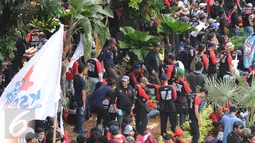 Massa buruh beristirahat di taman pembatas jalan di sekitar Kawasan Patung Patung Arjuna Wiwaha saat aksi perayaan hari Buruh Internasional 2017 di Jakarta, Senin (5/1). Ribuan massa buruh ikut turun ke jalan. (Liputan6.com/Helmi Fithriansyah)