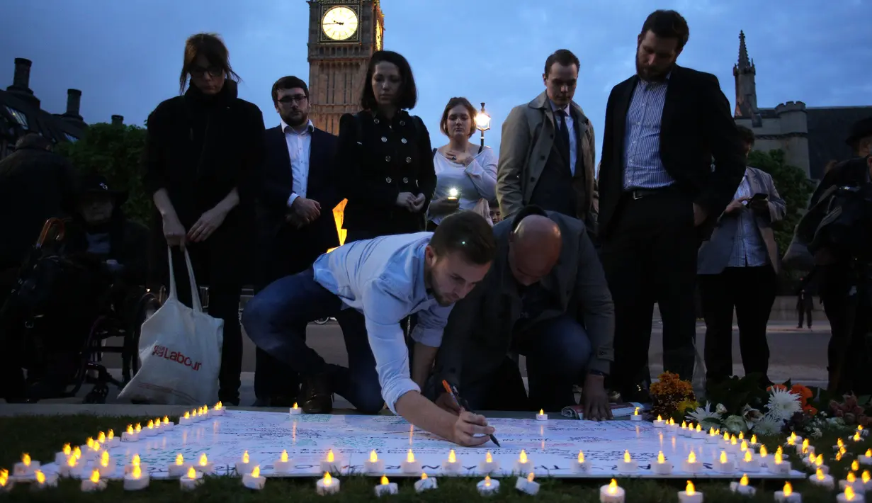 Warga menulis ucapan duka di spanduk putih untuk mengenang kematian tragis anggota parlemen Inggris, Jo Cox (41) di alun-alun parlemen, London, Kamis (16/6). Jo Cox diserang ketika hendak menemui konstituennya di Birstall. (Daniel Leal-Olivas/AFP)