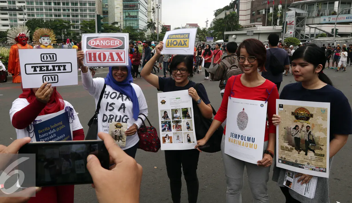Mafindo berfoto sambil menunjukan poster di hari bebas kendaraan bermotor di kawasan Thamrin, Jakarta, Minggu (22/1).  Akibat banjirnya informasi maka masyarakat harus berhati-hati dengan informasi yang tidak benar atau hoax. (Liputan6.com/JohanTallo)