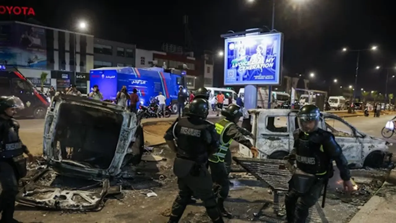 Aparat keamanan membersihkan puing-puing di dekat kendaraan yang dibakar saat demonstrasi Gen Z menuntut reformasi sektor kesehatan dan pendidikan di Sale, Maroko, pada Rabu (1/10/2025).