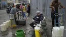 Warga memanfaatkan hidran kebakaran untuk mengisi wadah mereka dengan air di lingkungan San Juan di Caracas, Venezuela (19/1/2021). Venezuela merupakan negara dengan salah satu cadangan minyak terbesar di dunia. (AP Photo/Matias Delacroix)