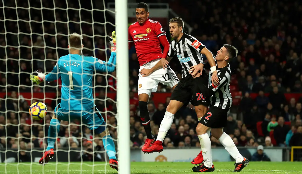 Pemain Manchester United, Chris Smalling (tengah) berhasil mencetak gol ke gawang Newcastle United pada laga lanjutan Premier League pekan ke-12 di Old Trafford, Minggu (19/11). MU menang telak 4-1 atas Newcastle. (Martin Rickett/PA via AP)