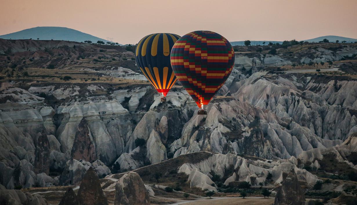 Balon udara membawa wisatawan naik ke langit saat matahari terbit di Kapadokia, Turki, Selasa (7/8). Kapadokia memiliki sejumlah keajaiban alam, khususnya Cerobong Peri (Fairy Chimney). (AP Photo/Emrah Gurel)
