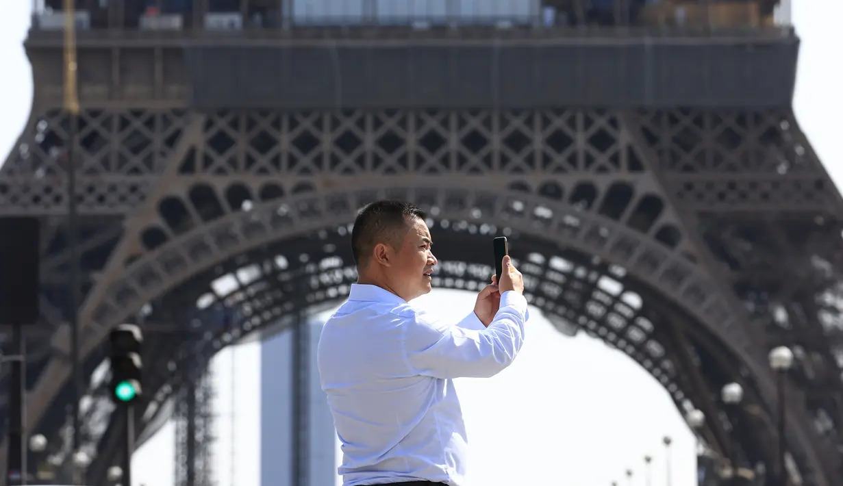 Seorang turis mengambil gambar dekat Menara Eiffel di Paris, Rabu (31/8/2022). Pariwisata kembali dengan sepenuh hati ke Prancis musim panas ini, mengirimkan pendapatan melebihi tingkat pra-pandemi menurut data pemerintah yang dirilis minggu ini. (AP Photo/Aurelien Morissard)