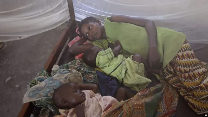 Foto yang diambil lewat kelambu nyamuk, dua anak dengan malaria beristirahat bersama ibunya di sebuah rumah sakit setempat di sebuah desa kecil di Walikale, Kongo (AP)