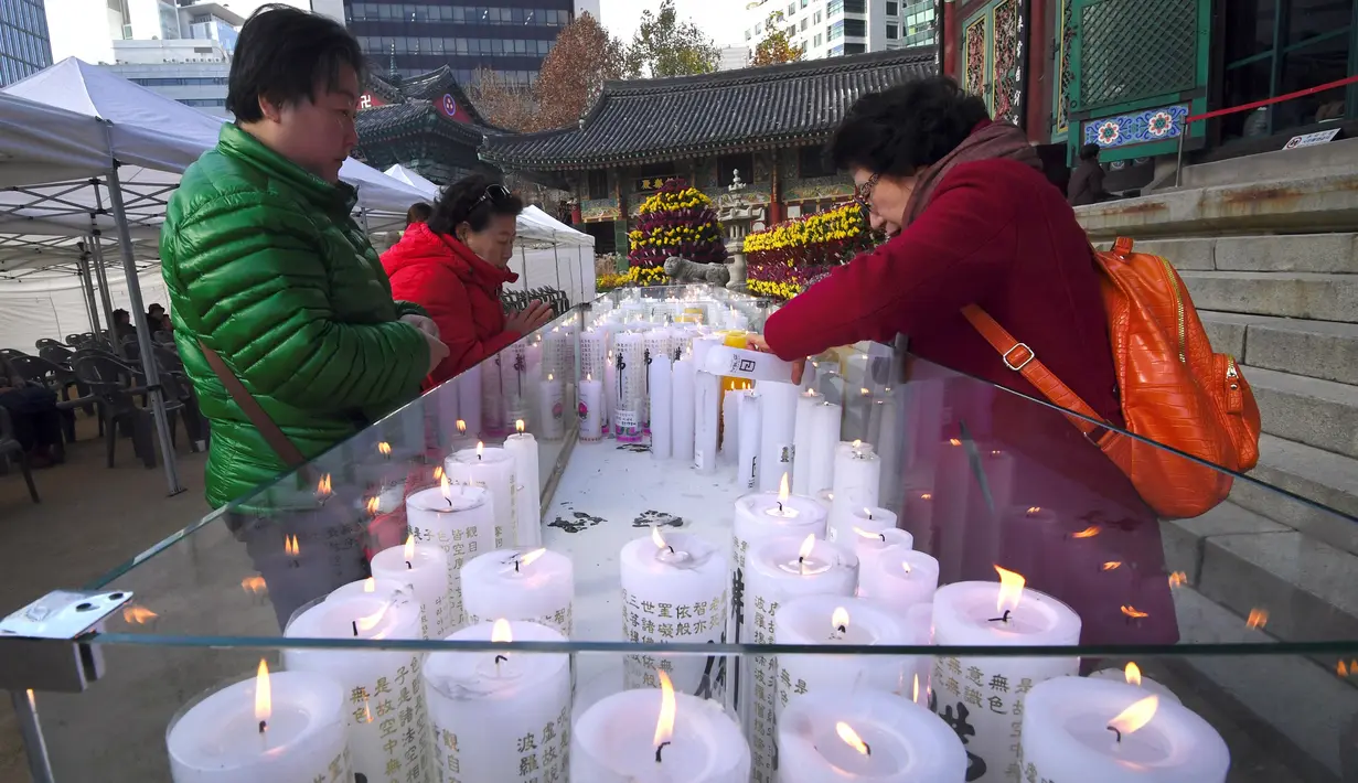 Sejumlah orang menyalakan lilin sambil berdoa untuk keberhasilan anak dan kerabatnya dalam mengikuti tes kemampuan Skolastik College tahunan di Seoul (23/11). (AFP Photo/Jung Yeon-Je)