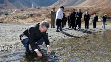 Presiden Korea Selatan Moon Jae-in memasukkan air kawah ke dalam botol di Gunung Paektu, Korea Utara, Kamis (20/9). Gunung Paektu merupakan gunung berapi yang dianggap sakral di Korea Utara. (Pyongyang Press Corps Pool via AP)