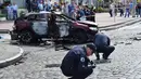 Petugas ahli forensik Ukraina memeriksa lokasi tewasnya jurnalis investigasi ternama, Pavel Sheremet di Kiev, Rabu (20/7). Jurnalis Ukrayina Pravda itu sedang mengendarai mobil ke tempat kerja ketika mobil tersebut meledak. (Sergei SUPINSKY/AFP)