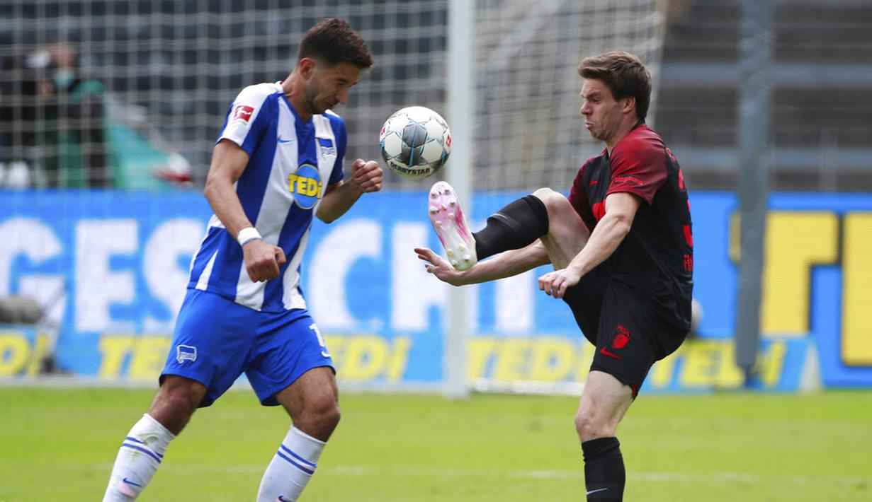 Pemain Hertha Berlin, Marko Grujic, berebut bola dengan pemain Augsburg, Raphael Framberger, pada laga Bundesliga di Olympiastadion, Sabtu (30/5/2020). Hertha Berlin menang 2-0 atas Augsburg. (AP/Hannibal Hanschke)