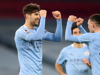 Bek Manchester City, John Stones (kiri) melakukan selebrasi dengan gelandang Phil Foden usai mencetak gol ketiga timnya ke gawang Crystal Palace dalam laga lanjutan Liga Inggris 2020/21 di Etihad Stadium, Minggu (17/1/2021). Manchester City menang 4-0 atas Crystal Palace. (AFP/Clive Brunskill/Pool)