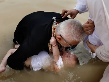 Imam Kristen Ortodoks Serbia membaptis seorang bayi di perairan Sungai Yordan di dekat kota Jericho (4/3). Di tempat ini diyakini Yesus Kristus dibaptis oleh Yohanes Pembaptis. (AFP Photo/Gali Tibbon)
