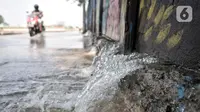 Pengendara motor melintasi rembesan air dari tembok saat banjir rob merendam Kompleks Perumahan Pantai Mutiara, Pluit, Jakarta, Minggu (7/6/2020). (merdeka.com/Iqbal S. Nugroho)