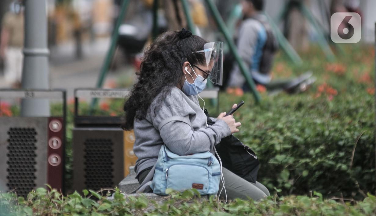 Pekerja yang memakai face shield menunggu jemputan di kawasan Sudirman, Jakarta, Senin (14/9/2020). Selama PSBB, Pemprov DKI Jakarta mewajibkan perusahaan nonesensial untuk membatasi 25 persen dari total pekerja yang bekerja di kantor guna memutus penyebaran Covid-19. (merdeka.com/Iqbal S. Nugroho)