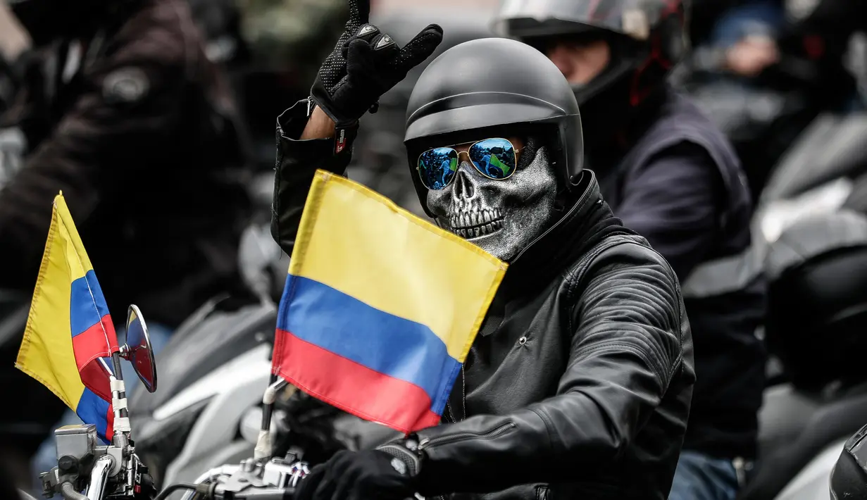 Seorang pengendara sepeda motor memberi isyarat selama protes kenaikan harga bahan bakar di Bogota, Kolombia, Rabu (12/10/2022). Aksi protes ini muncul karena kenaikan harga bahan bakar dan asuransi wajib pihak ketiga. (AP Photo/Ivan Valencia)