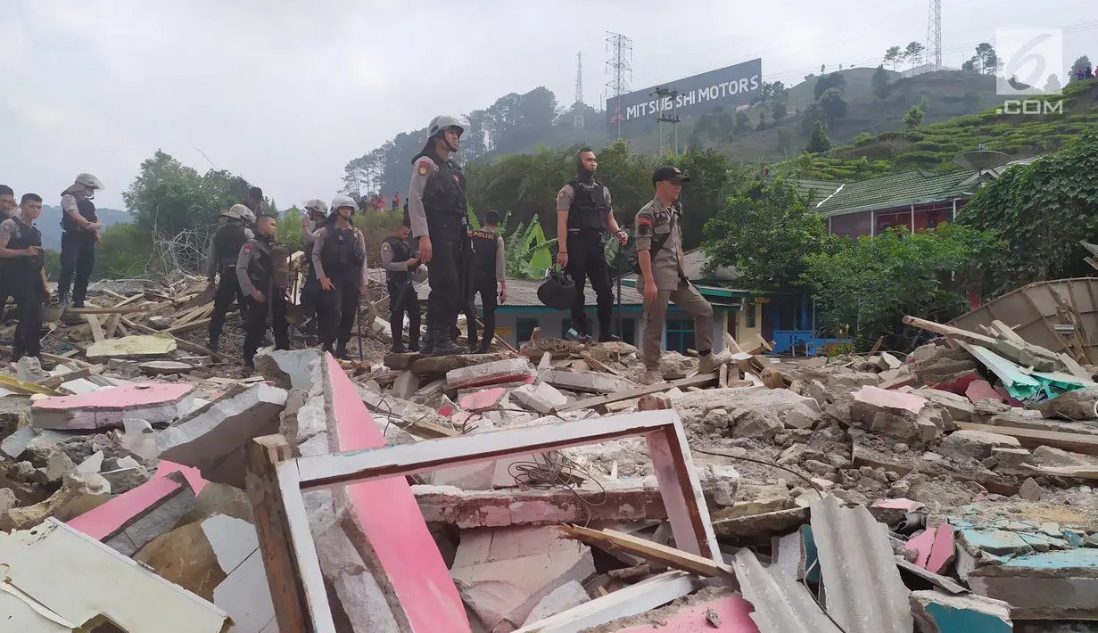 Personel Polres Bogor berdiri di atas sisa reruntuhan bangunan yang dibongkar di Kampung Naringgul, Kabupaten Bogor, Kamis (29/8/2019). Puluhan bangunan rumah yang sebagian merupakan penginapan dan rumah kos-kosan tersebut dibongkar Satpol PP lantaran tidak memiliki izin. (Liputan6.com/Alby Azka)
