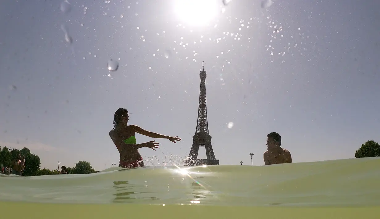 Turis dan warga menyejukkan diri dengan berendam di kolam Trocadero Fountains (air mancur Trocadero) dekat Menara Eiffel di Paris, Kamis (25/7/2019). Gelombang panas di Eropa mencapai puncaknya, bahkan suhu di ibu kota Prancis mencapai di atas 41 derajat Celcius. (Dominique FAGET / AFP)