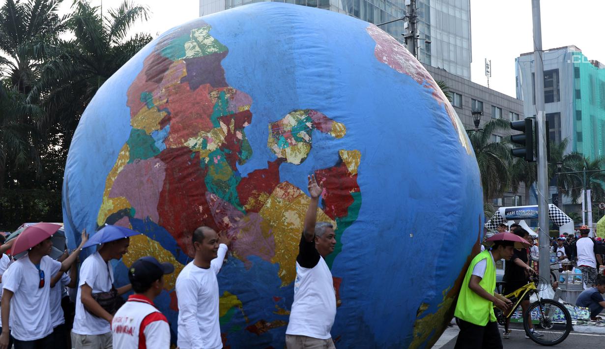 Replika bola dunia berukuran besar digelindingkan di sekitar kawasan Bundaran HI, Jakarta, Minggu (16/9). Acara ini bagian dari peringatan Hari Ozon Sedunia 2018 dengan tema Keep Cool and Carry on! The Montreal Protocol. (Liputan6.com/Helmi Fithriansyah)