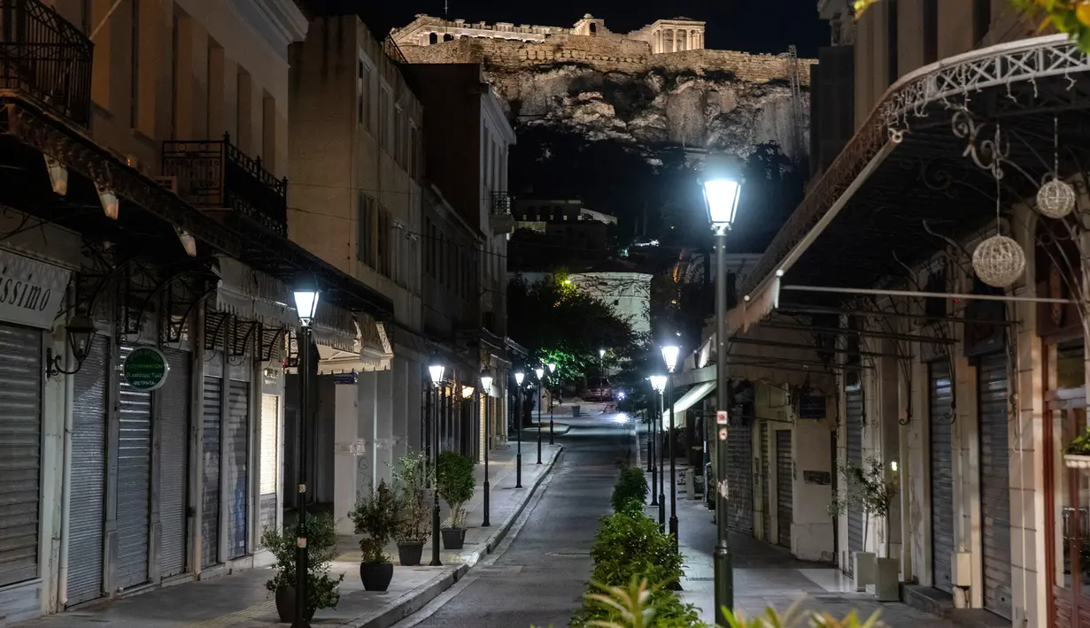 Pemandangan jalan kosong dengan latar belakang bukit Acropolis di Athena, Yunani, Minggu (25/10/2020). Pemerintah Yunani telah memberlakukan jam malam di Athena, Thessaloniki, dan daerah lain dengan tingkat infeksi COVID-19 yang tinggi serta kewajiban penggunaan masker. (AP Photo/Yorgos Karahalis)