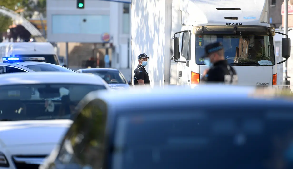 Petugas polisi setempat mengontrol pergerakan orang di sebuah pos pemeriksaan lalu lintas di kota Fuenlabrada yang tertutup sebagian, di wilayah Madrid (22/9/2020). Penguncian dilakukan akibat infeksi virus melonjak. (AFP/Oscar Del Pozo)