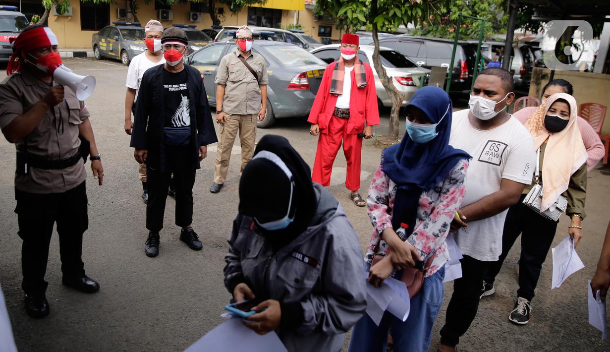 Petugas kepolisian berpakaian pejuang jaman dulu saat memberikan pengarahan kepada warga yang akan ikut vaksin Covid-19 di Polsek Pasar Rebo, Jakarta, Selasa (17/8/2021). Para petugas berkostum pejuang jaman dulu memeriahkan HUT ke-76 Republik Indonesia. (Liputan6.com/Angga Yuniar)