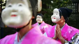 Seniman mengenakan Otafuku tradisional Jepang atau topeng Okame selama Festival Konpira di kuil Kotohiragu di distrik bisnis Toranomon di Tokyo (10/1/2020). Selain topeng tradisional, seniman pakaian tradisional khas negeri tersebut. (AP Photo/Eugene Hoshiko)