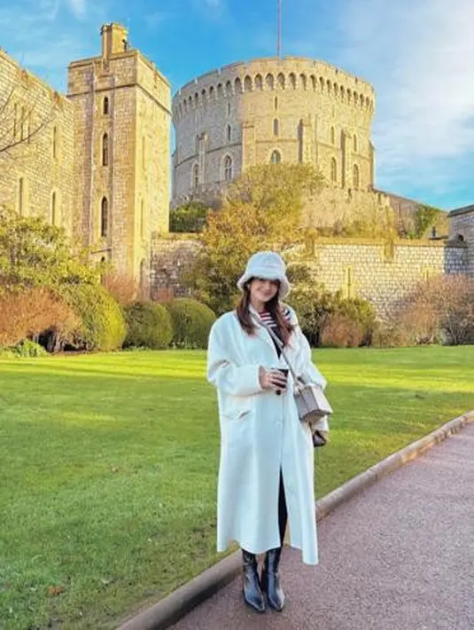 Enzy terlihat cantik mengenakan long coat putih di atas knit top. Penampilannya makin stylish dengan faux fur hat dan sepatu boots. @enzystoria/@hestipurwadinata.