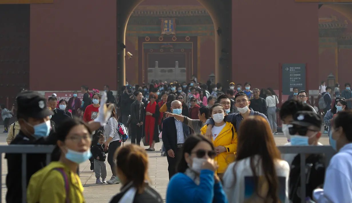 Pengunjung mengenakan masker untuk mencegah penyebaran virus corona keluar dari Kota Terlarang di Beijing, Rabu, (7/10/2020). Menurut kementerian budaya dan pariwisata China, libur Hari Nasional menghasilkan $ 45,9 miliar pendapatan pariwisata. (AP Photo/Andy Wong)