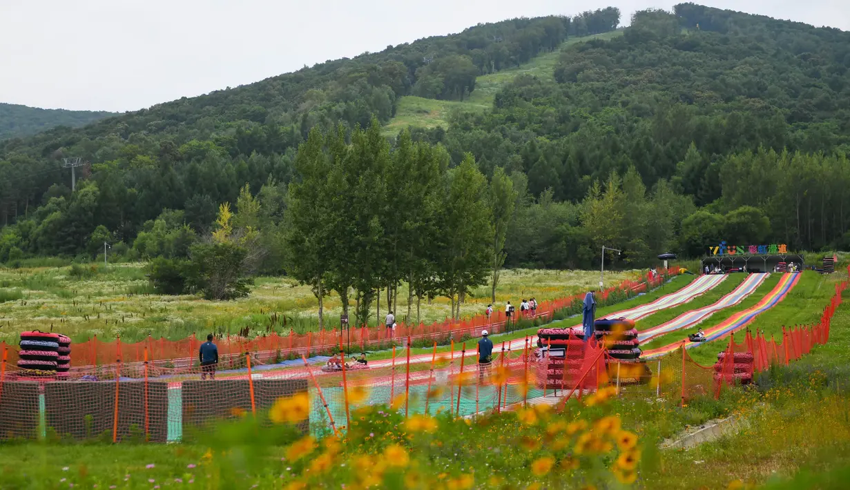 Warga bermain seluncuran yang ada di sebuah kawasan resor di Kota Jilin, Provinsi Jilin, China pada 19 Juli 2020. Arena ski di kawasan resor itu diubah menjadi ladang bunga, seluncuran, dan beragam proyek pariwisata rekreasi lainnya guna menarik wisatawan pada musim panas. (Xinhua/Yan Linyun)
