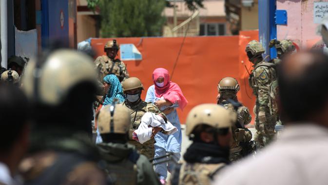 Seorang anggota keamanan dan seorang pekerja kesehatan menggendong bayi dari lokasi serangan di sebuah rumah sakit di Kabul, ibu kota Afghanistan (12/5/2020).  (Xinhua/Rahmatullah Alizadah)