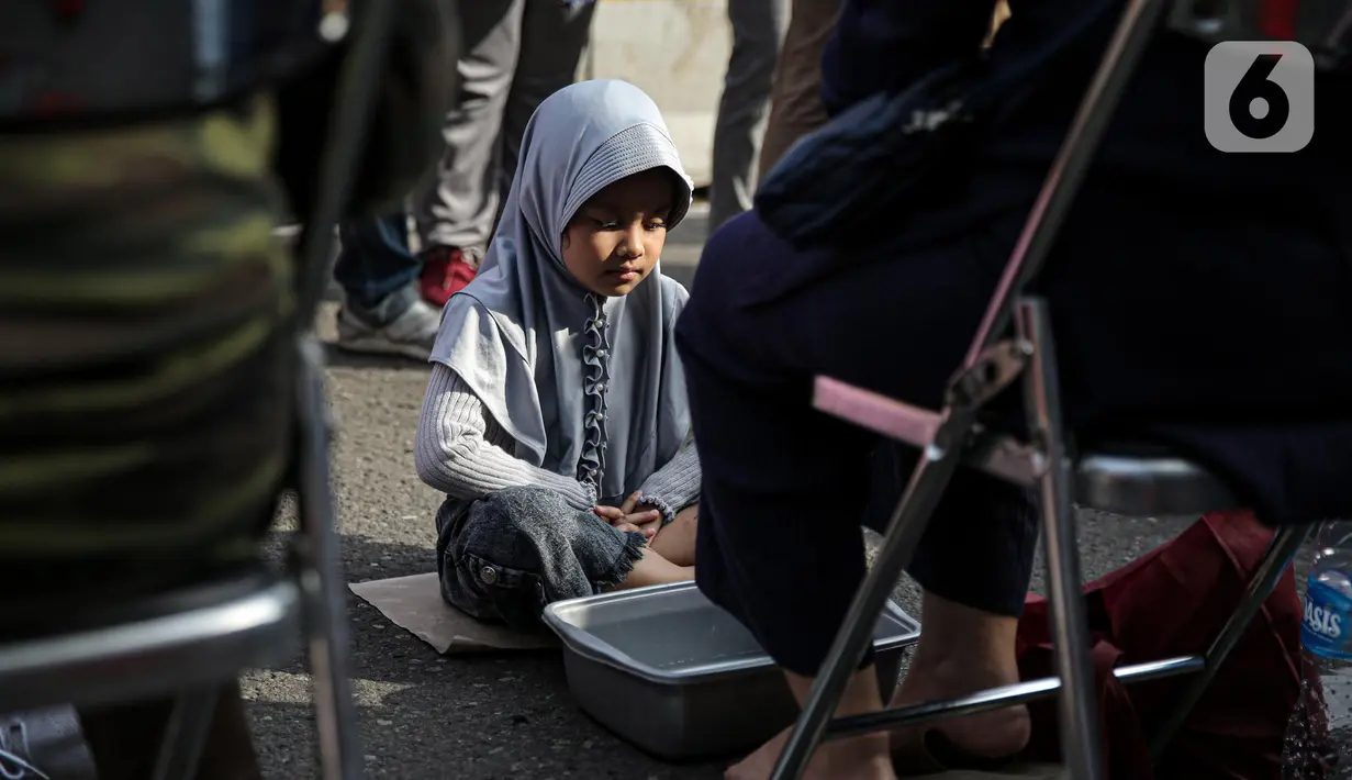 Seroang anak akan mencuci kaki ibunya pada aksi cuci kaki ibu massal di Jakarta, Minggu (18/12/2022). Aksi yang diikuti sebanyak ratusann peserta itu bertujuan untuk meningkatkan rasa cinta kasih kepada ibu , khususnya dalam rangka memperingati Hari Ibu. (Liputan6.com/Faizal Fanani)