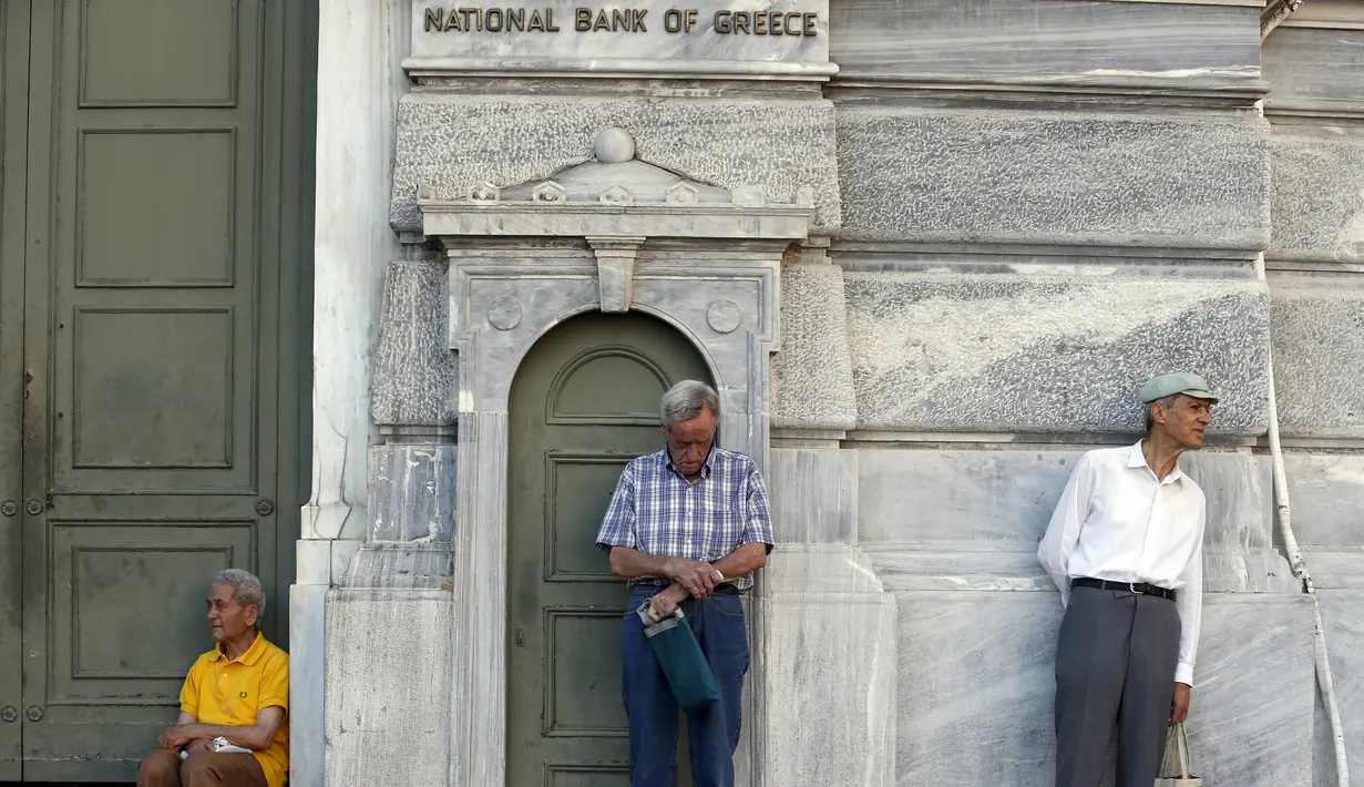 Pensiunan menunggu di depan pintu masuk Bank Nasional untuk menerima bagian dari dana pensiun mereka di Athena, Yunani (9/7/2015). Banyak bank di Yunani tutup dan penarikan uang tunai dari ATM dibatasi hanya 67 dolar sehari. (REUTERS/Jean Paul Pelissier)