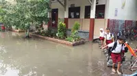 Siswa SDN Genuksari 2 melintasi genangan air di sekolahnya